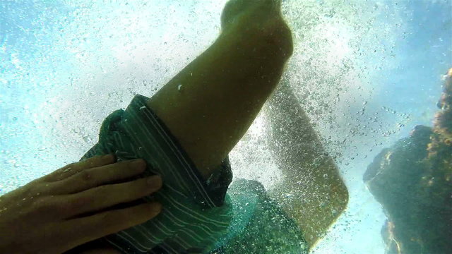 An underwater shot of a jumping man against bright sunshine.Slow motion video.