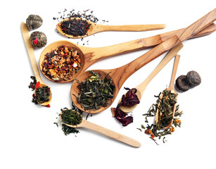 Different sorts of dry tea in wooden spoons, isolated on white
