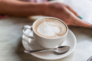 Cappuccino in white cup and woman hand