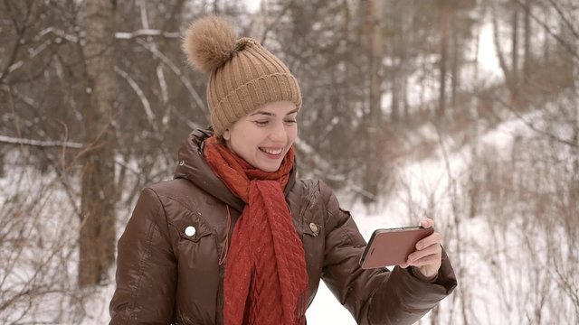 Girl taking a selfie in a winter forest with a smartphone