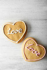 Two Valentine heart cookies on wooden background