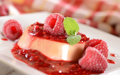 Panna cotta dessert with fresh raspberries and mint leaves on to