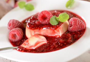 Panna cotta dessert with fresh raspberries and mint leaves on to