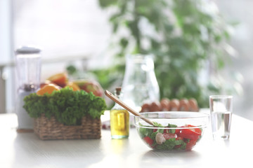 Vegetable salad in glass bowl and other products on table in the kitchen