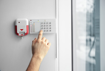 Security alarm keypad with male hand, closeup