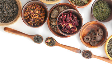 Variety of dry tea in pots and wooden spoons isolated on white, copy space