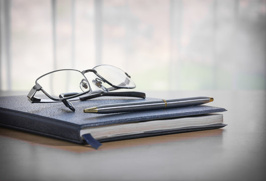 Glasses and pen on a book