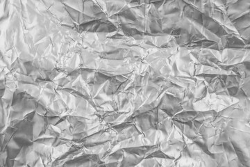 Silver foil background with shiny crumpled uneven surface