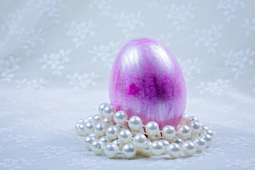 Pink Easter Egg on pearls with blurry lace background