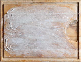 Rough wooden rectangular used cutting board background with flour directly from above