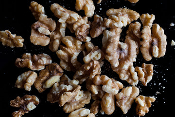 Shelled walnuts on black background directly from above
