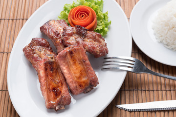fried pork spare ribs on the white dish with a rose make from tomato on the side