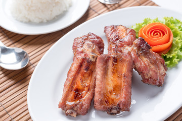 fried pork spare ribs on the white dish with a rose make from tomato on the side