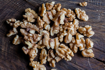 Shelled walnuts on wooden cutting board background directly from above