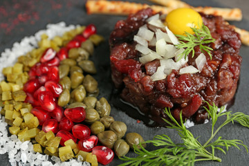 Delicious beef tartare with ingredients, closeup