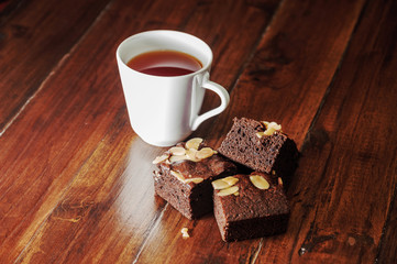 Chocolate brownies and cup of tea on wooden table