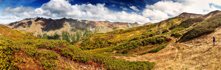 Fototapeta na wymiar Vivid panorama of the Caucasian mountains in autumn Sunny with hiker team