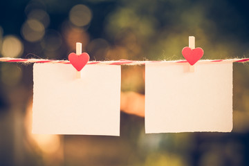 2 Blank white paper and red clip paper heart hanging on the clothesline with bokeh nature background.Designer concept.vintage or retro tone. - Powered by Adobe