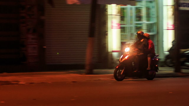 Night Scooter Traffic along Street by Shop-windows