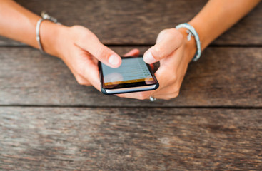 young cute girl hipster, sitting at a cafe holding a smart phone, answering texts, phone calls, letters, posts photos in instagram, outdoor portrait, close up, elaborated and bracelets on the hands