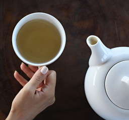 Tea time. Girl holding a cup of tea on the table