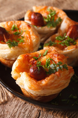 buns of puff pastry with sausage and cheese on a plate close-up. vertical
