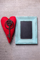 Red decorative  heart, vintage key and empty blackboard on slate