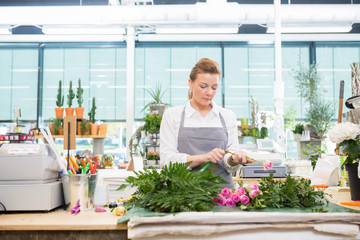 Florist Cutting Stem On Rose At Counter In Flower Shop