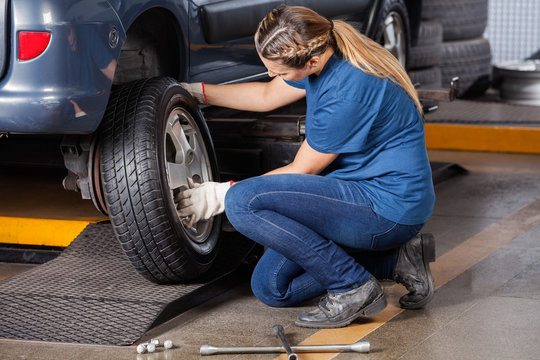 Mechanic Replacing Car Wheel At Repair Shop