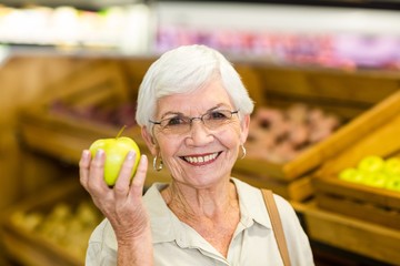 Fototapeta premium Senior woman holding and watching a green apple