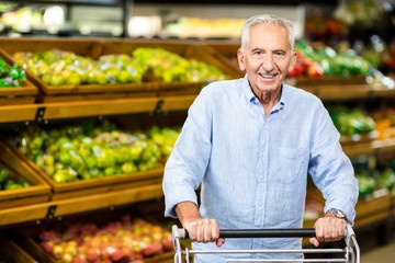 Smiling senior man holding trolley