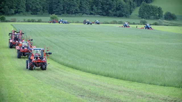 Few tractors is working on big green lawn
