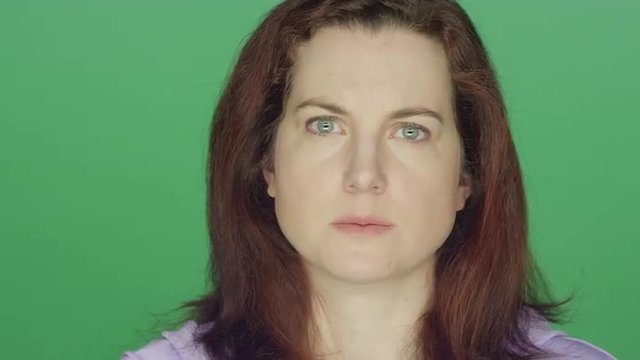 Young redhead woman looking worried, on a green screen studio background