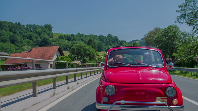 Small red zastava car passing a few houses