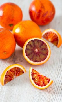 cut blood oranges on wooden surface