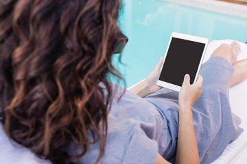Young woman using digital tablet near poolside