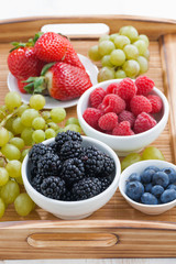 fresh berries in a bowl and green grapes on wooden tray