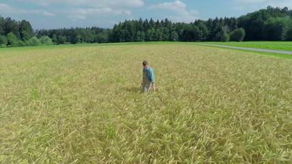 Farmer on sunny day is walking on the middle of the field
