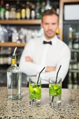 Handsome barman standing behind cocktails