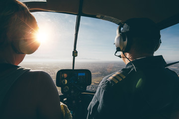 Two pilots in a helicopter while flying on a sunny day - obrazy, fototapety, plakaty