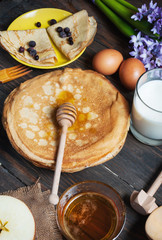 pancakes with honey and ingredients on wooden background