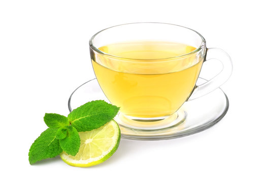 A cup of green tea with mint sprig and slice of lime isolated on a white background.