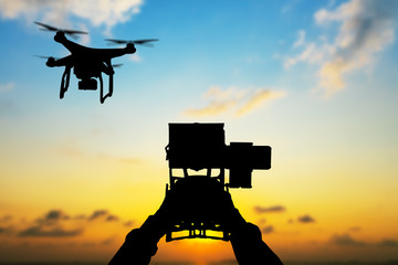 Man hands handling drone in sunset silhouettes
