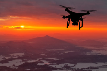 Drone silhouette flying in sunset landscape