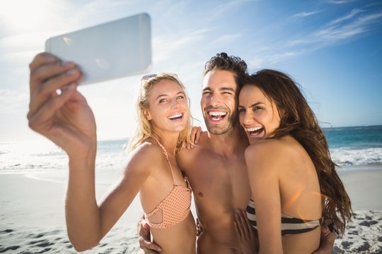 Happy friends taking selfie on the beach 