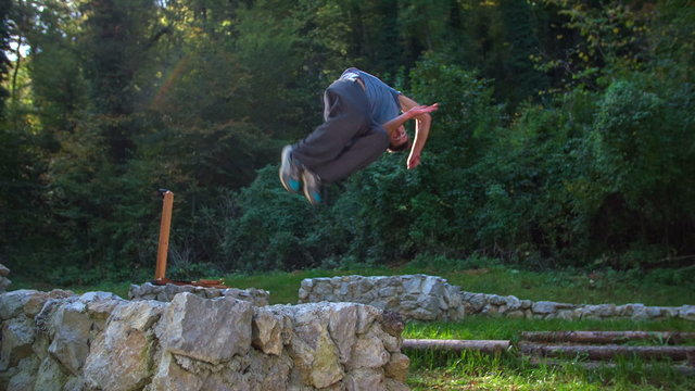 Young man doing 360 back-flip on the castle ruins.