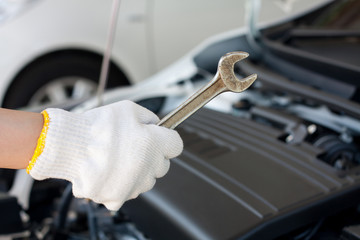Hand with wrench repairing car engine