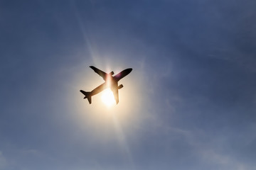 Silhouette airplane taking off over blue sky at sun background