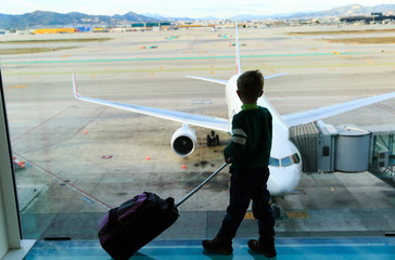 little boy with suitcase waiting in the airport