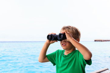 little boy with binoculars travel at sea 